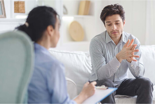 Мужчина и психолог с планшетом беседуют в кабинете